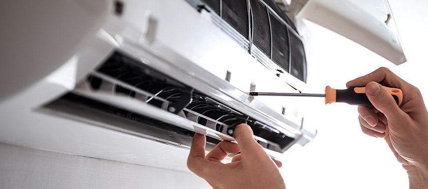 repair man fixing AC unit with screwdriver